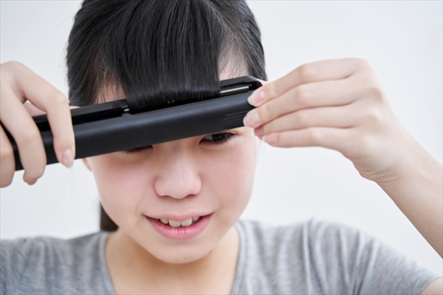 【中学生限定】雨の日の通学前に30秒!前髪キープできる簡単裏ワザ_女性がヘアアイロンで髪を伸ばす様子_01